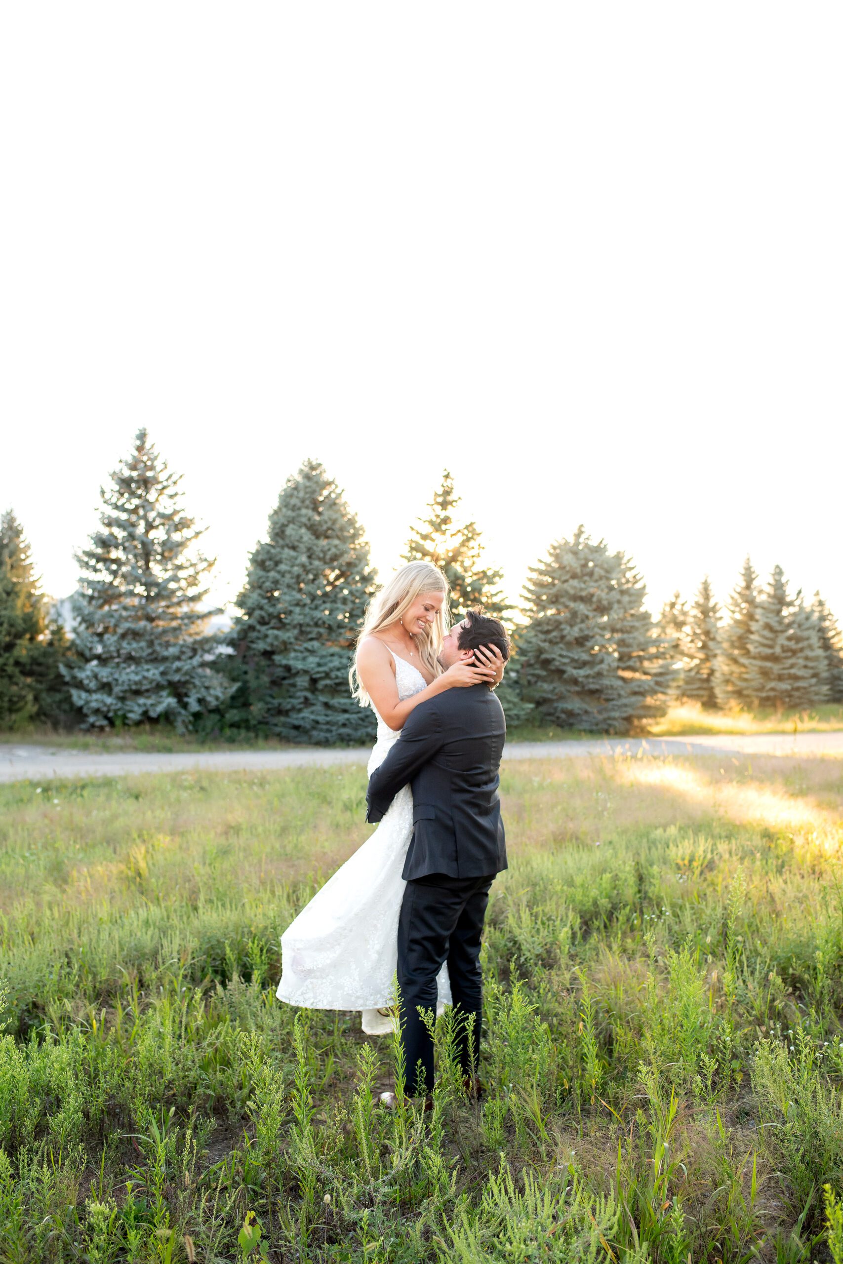 Groom spinning bride around at golden hour in field in Strathroy Ontario
