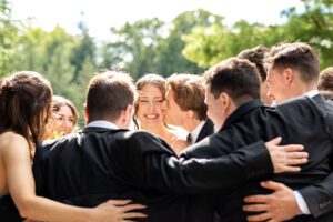 Groom kissing bride on cheek surrounded by wedding party after their wedding ceremony at Bellamere Winery.