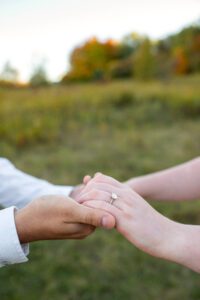 Close up of man holding woman's hand showcasing engagement ring at Lakeside Park in Kitchener Ontario.