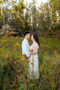 Couple looking at each out in field in the fall at Lakeside Park in Kitchener Ontario.