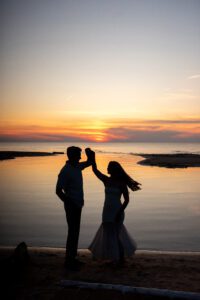 Silhouette of couple spinning at sunset on the beach in Port Franks Ontario.