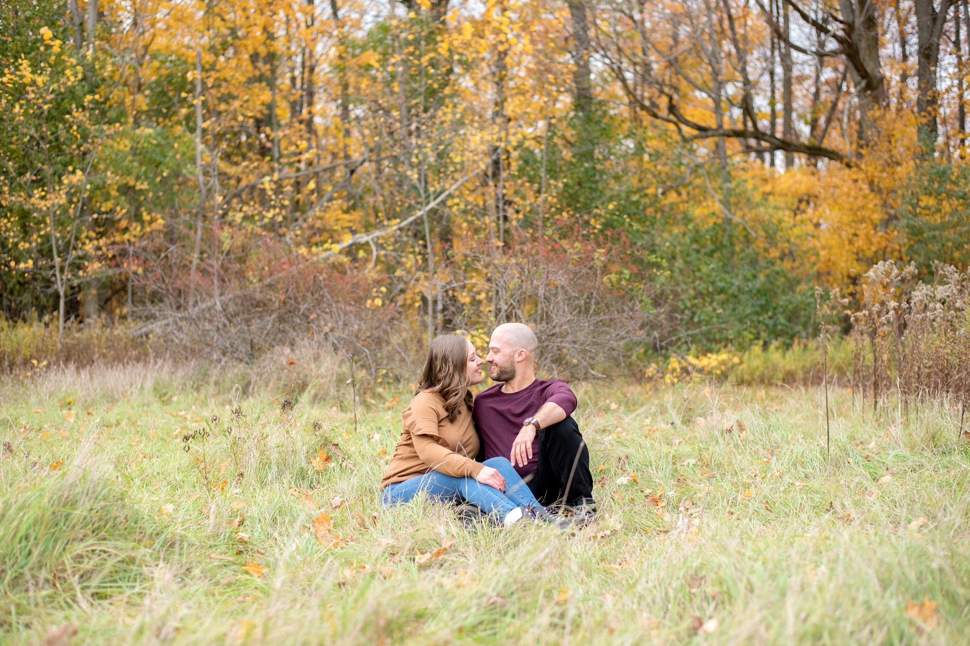 couple sitting in middle of field in the fall