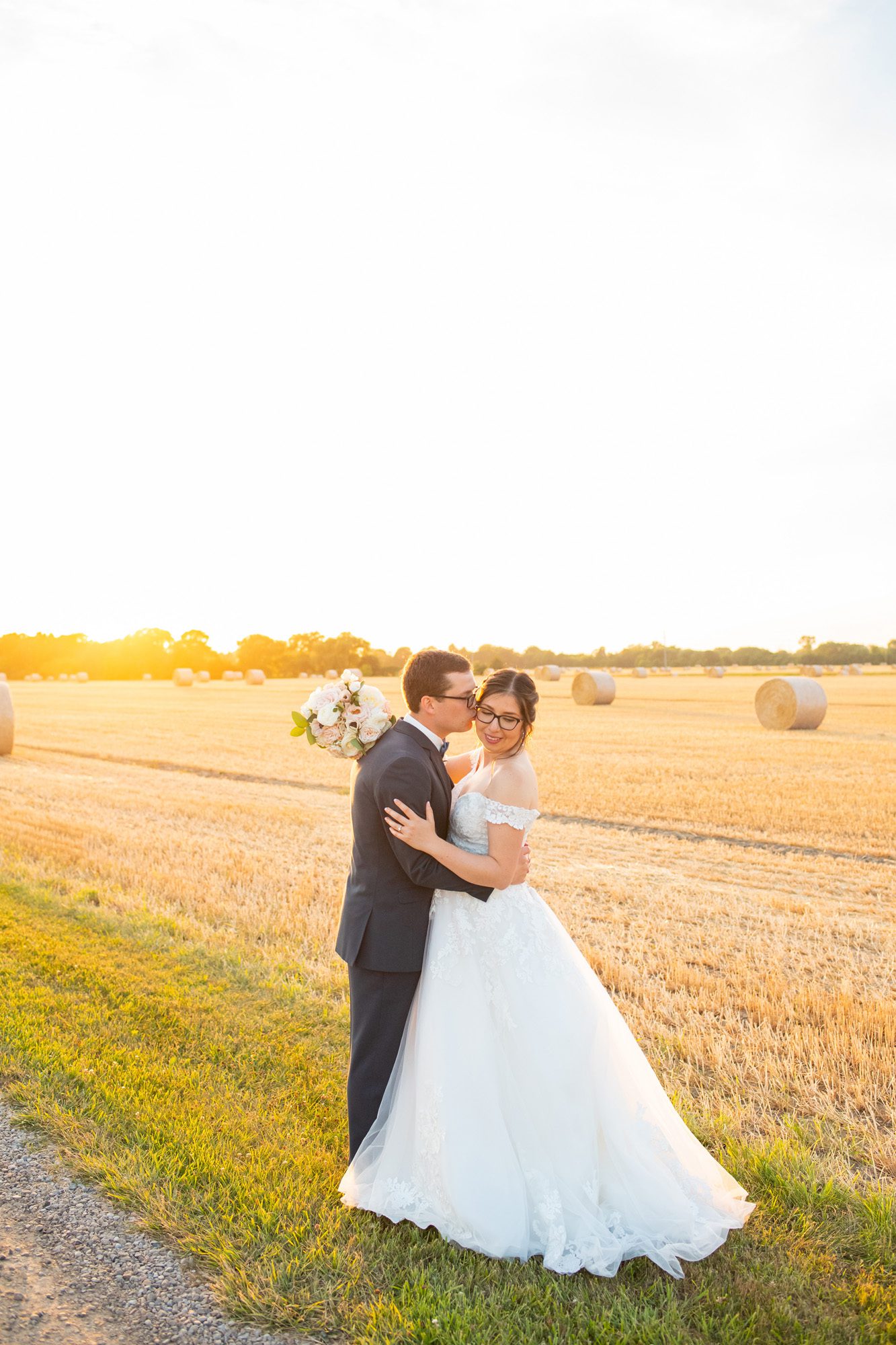 Groom kissing bride on cheek at golden hour at Hessenland Inn.