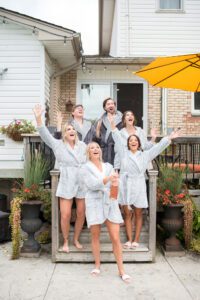 Bride and bridal party popping a bottle of champagne.