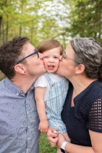 Mom and dad each kissing little boys cheek at Springbank Garden