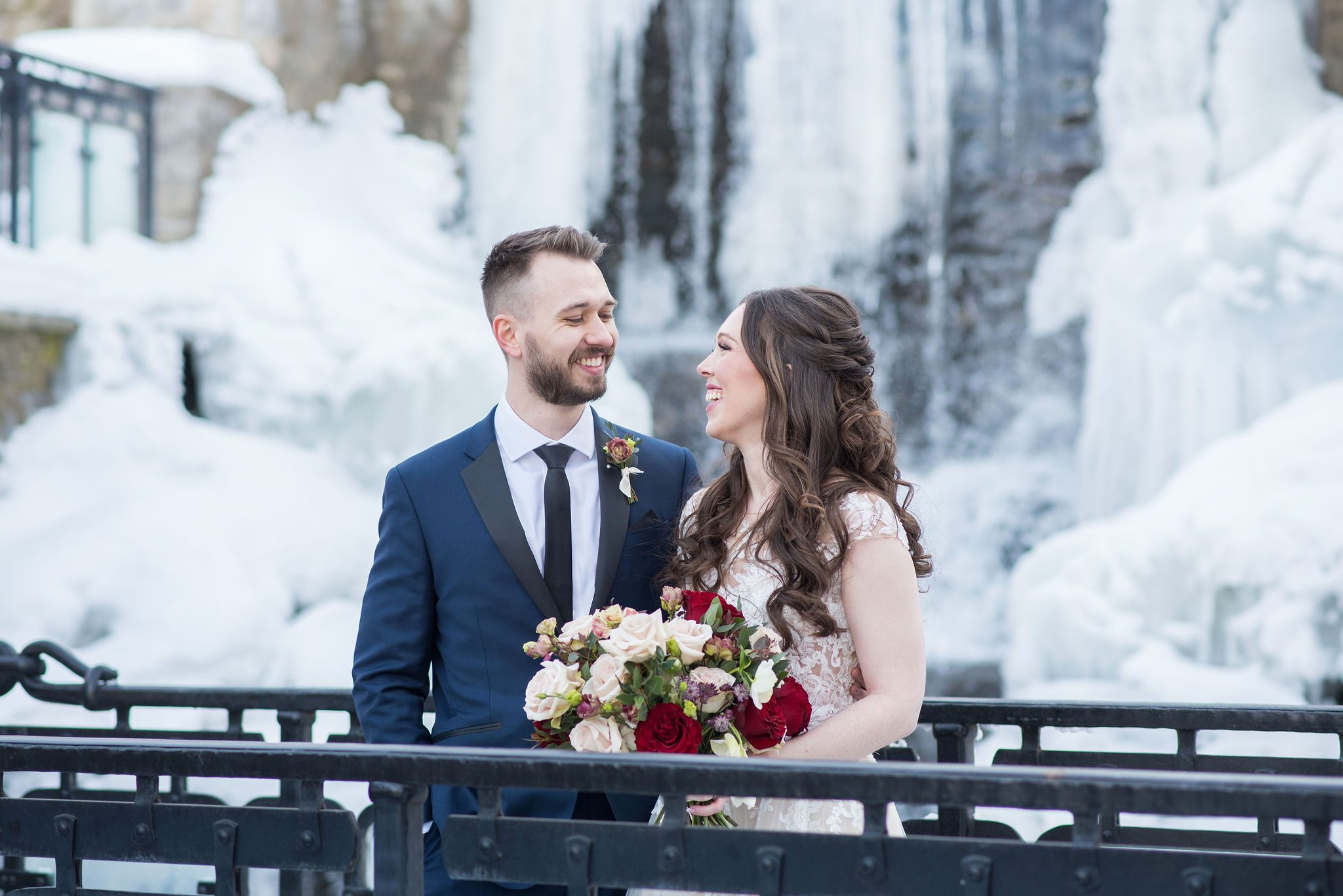 bride and groom in front of frozen waterfall at Ancaster Mill