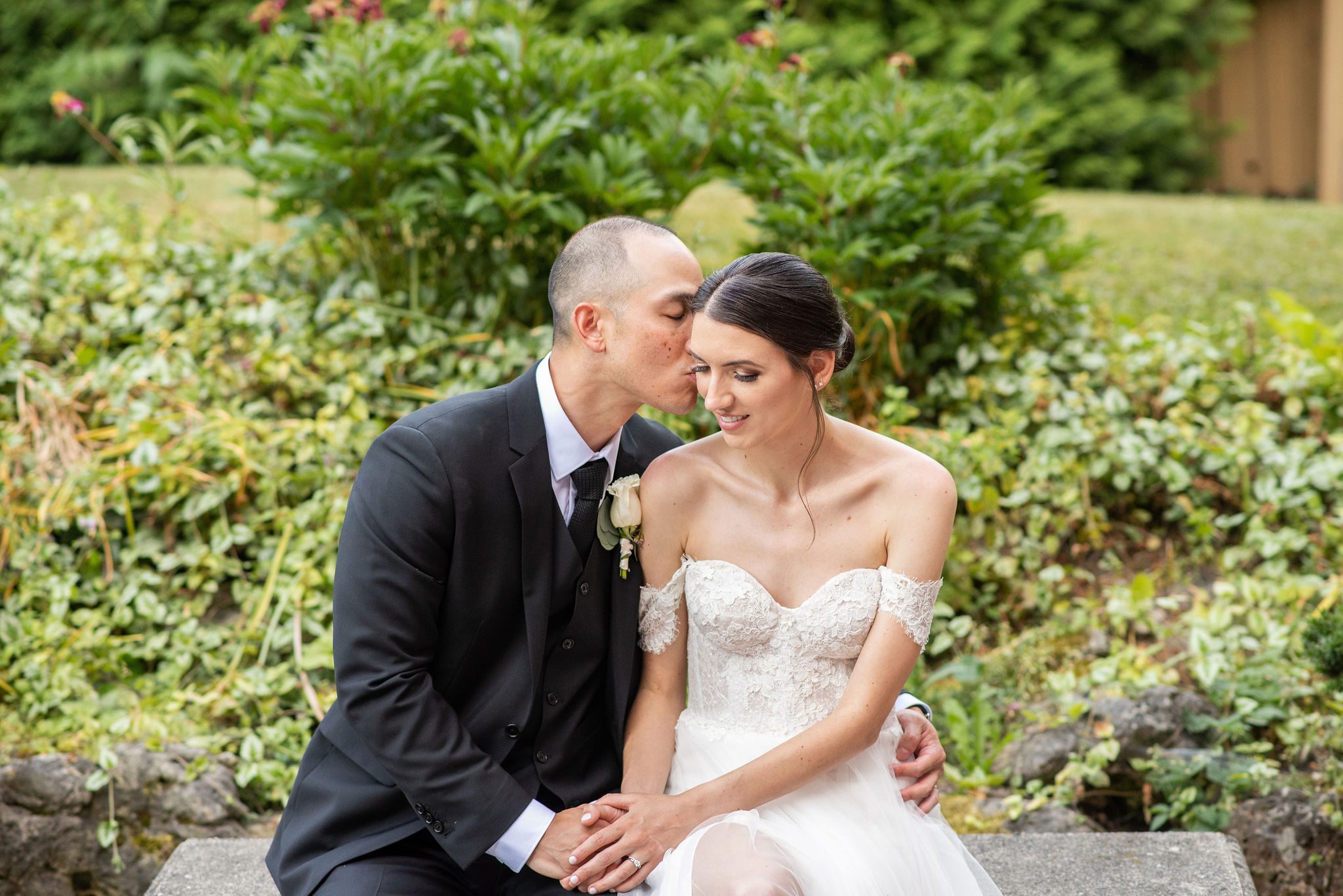 bride and groom sitting on stone bench