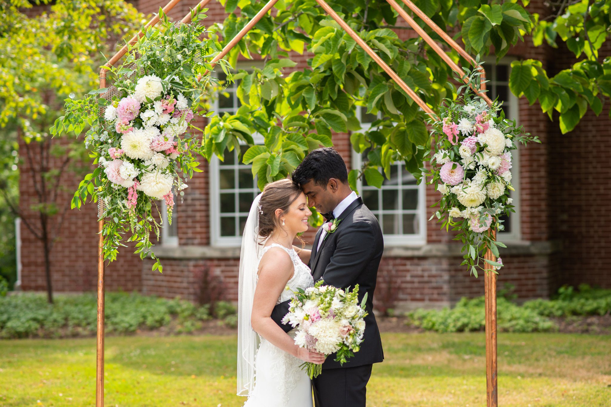 Bride and groom facing each other under their ceremony arch at Ivey Spencer.