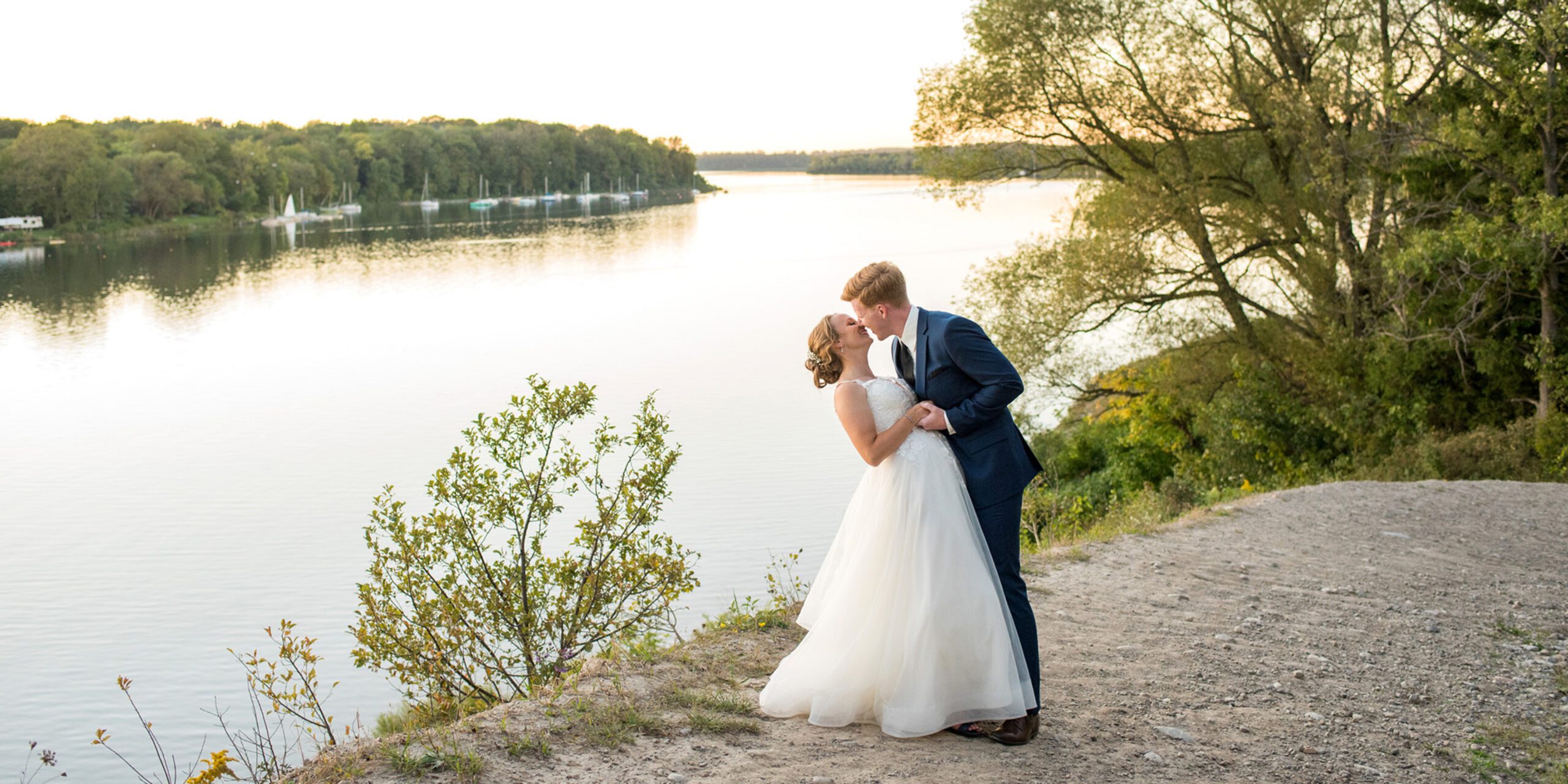 Groom dipping bride in front of the river at Forest City National Golf Course.
