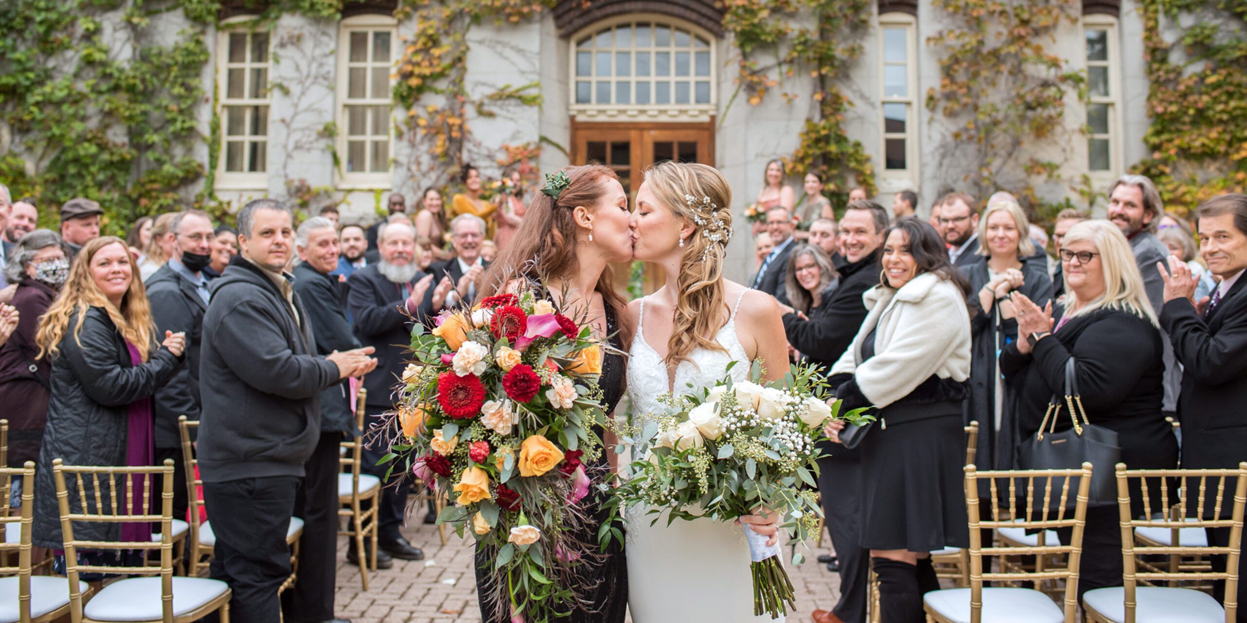 Bride and Bride kissing at the end of their wedding aisle at The Old Court House