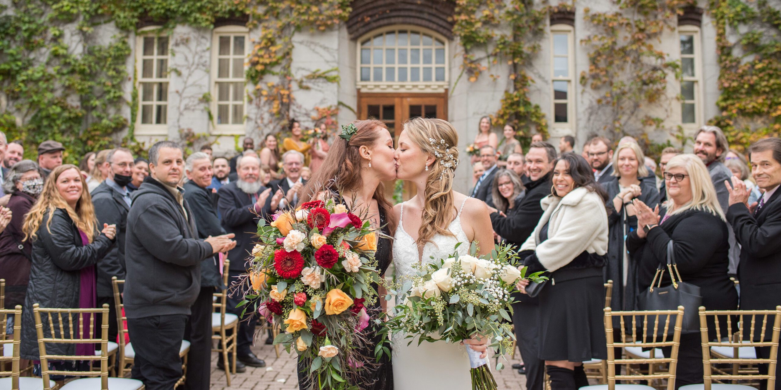 Brides kissing at the end of the ceremony aisle at The Old Court House.
