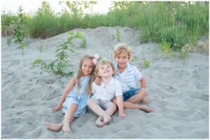 Three kids smiling at the camera at Port Stanley Beach.