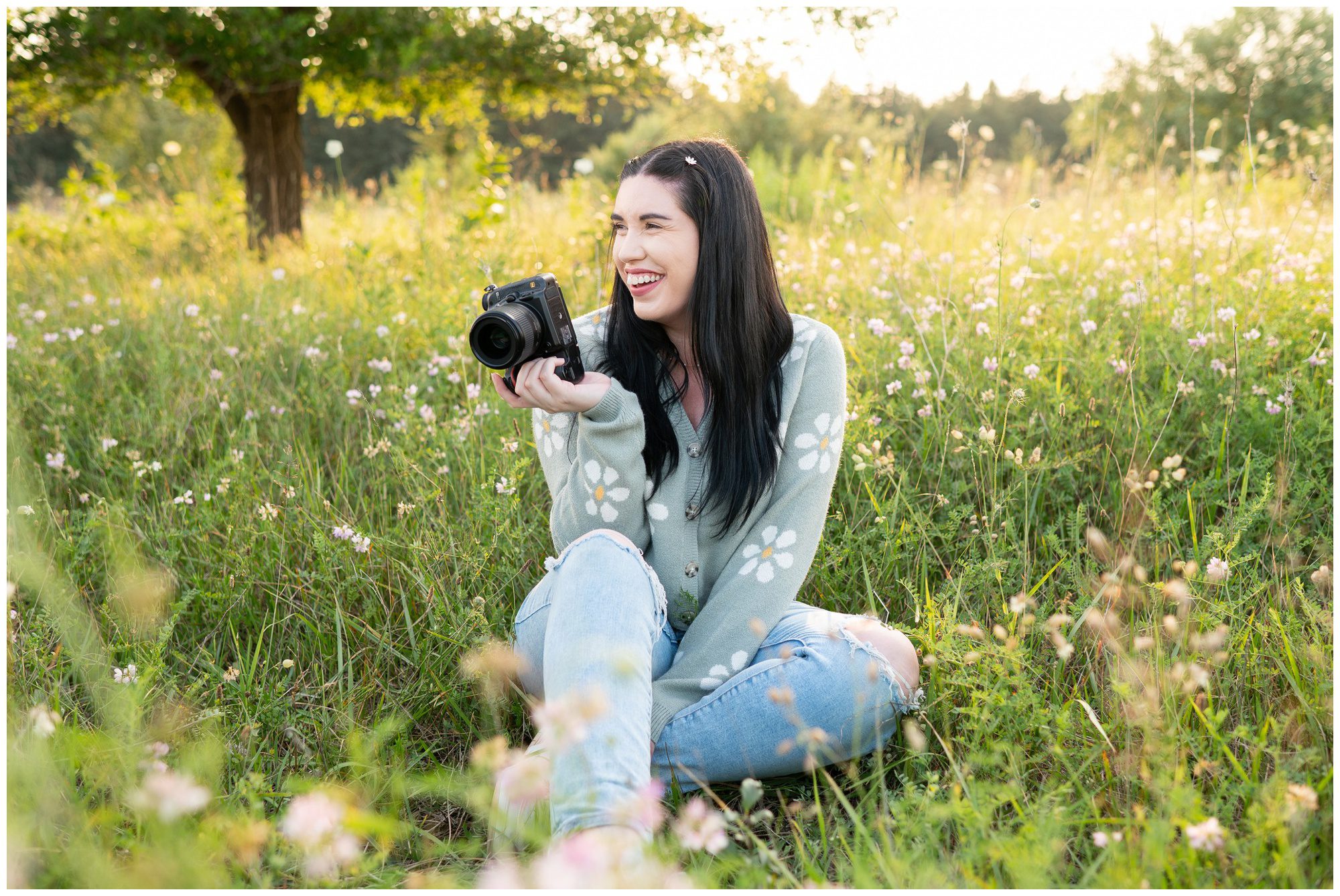 Michelle of Michelle A Photography sitting in a wild flower field with camera in London Ontario.