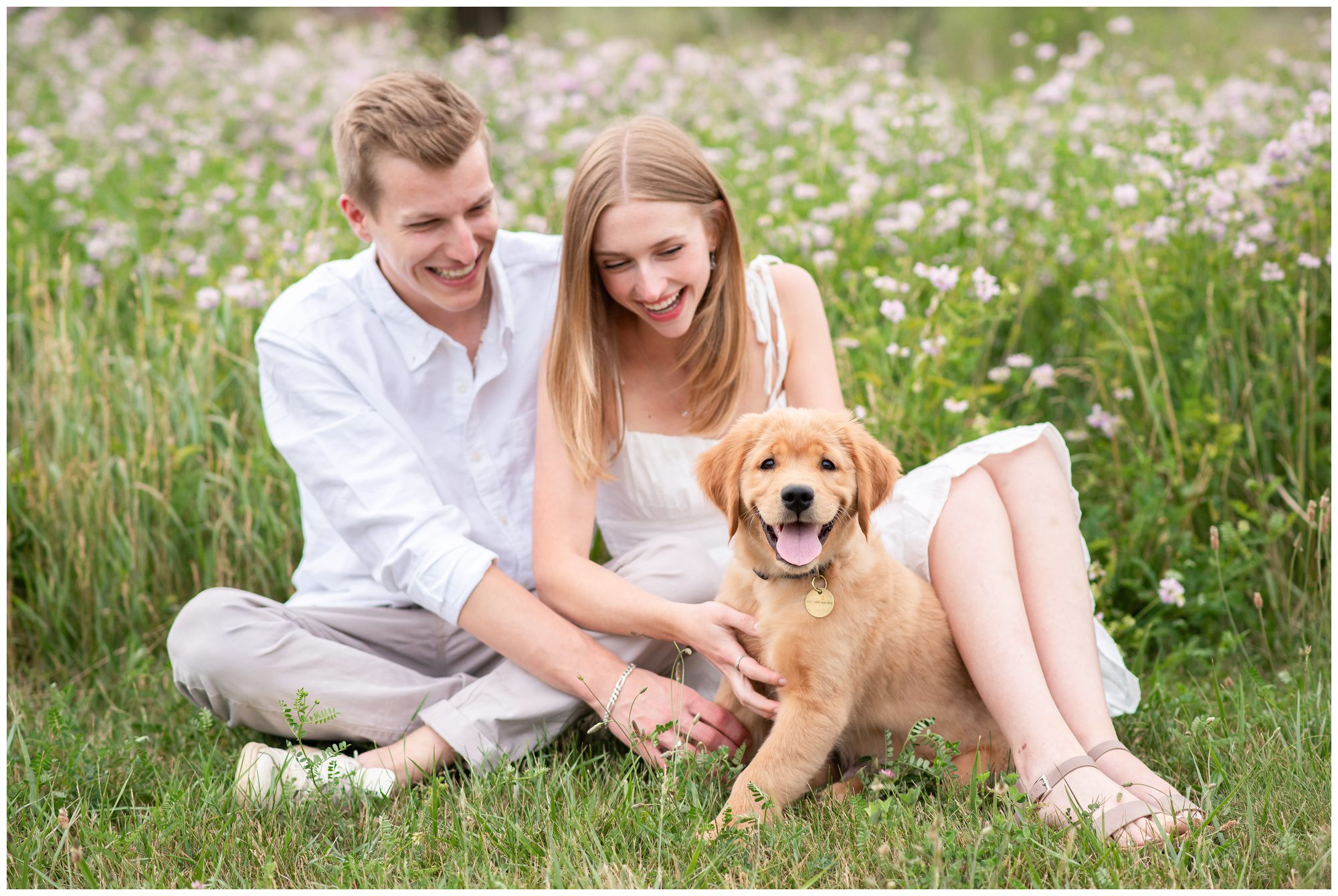 Young couple sitting in wildflower field with their 12 week old golden retriever puppy at Fanshawe Conservation Area