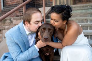 Bride and Groom kissing their chocolate lab at London City Hall, Downtown London Ontario.