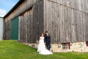 Bride and groom holding hands in front of barn.