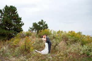 Bride and groom kissing and dipping surrounded by fall foliage.
