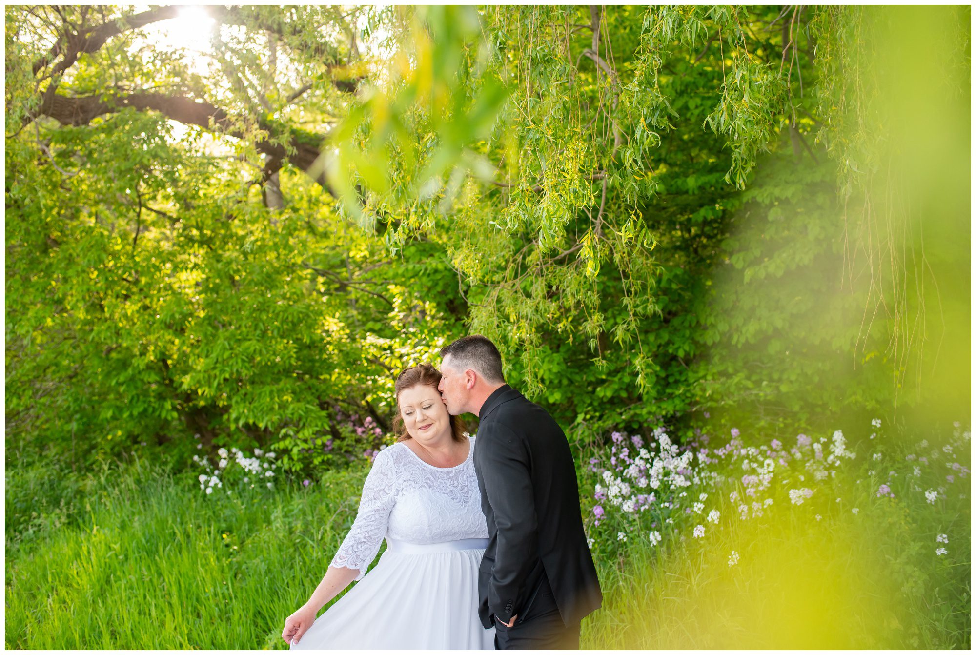 Groom kissing bride on cheek at little beach in Port Stanley Ontario.